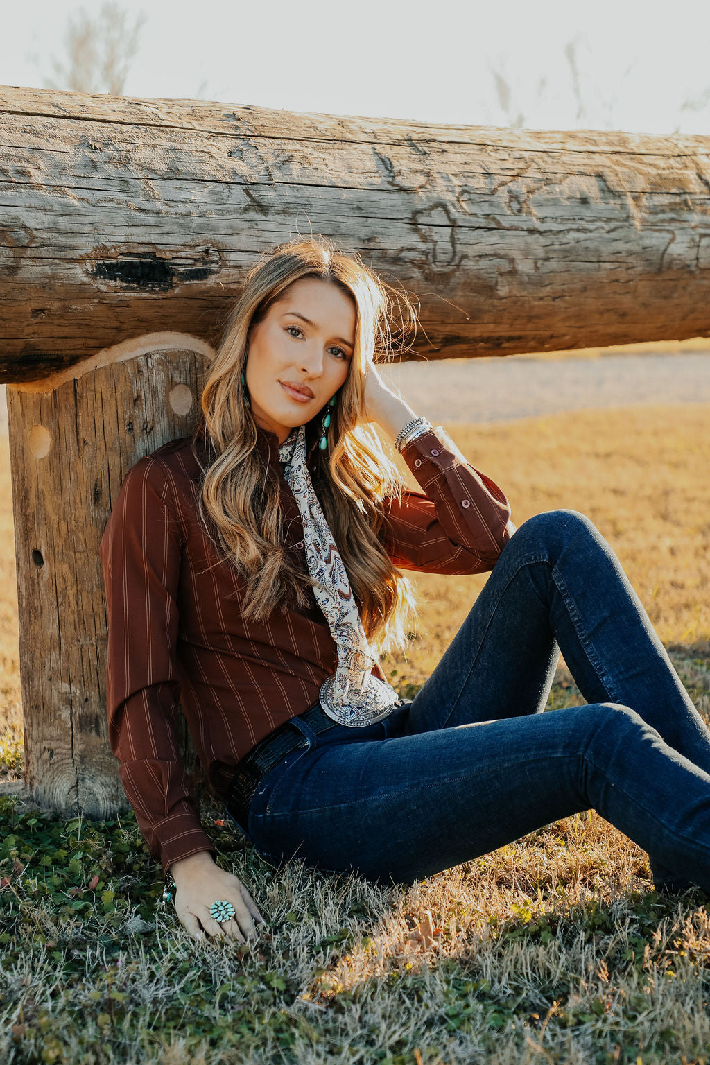 Woman sitting on grass next to a wooden log in a natural setting